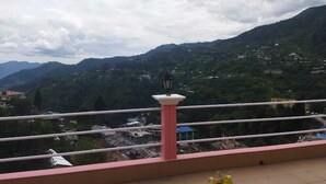Ein Balkon mit Blick auf eine gebirgige Landschaft, einer Lampe und einem Blumentopf.