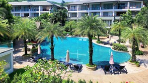 Ein Hotel mit einem großen Schwimmbecken, umgeben von Palmen und Liegestühlen.