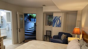 Ein Schlafzimmer mit einem Bett, einem Sessel, einer Lampe und einem Gemälde.