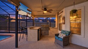 An outdoor kitchen area with a grill, a dining table, and chairs.