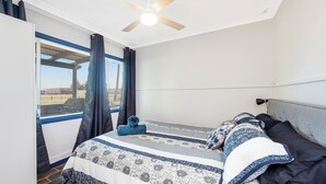 Ein Schlafzimmer mit einem Bett, einem Deckenventilator und einem Fenster mit Vorhängen.