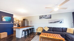 Ein moderner Wohnraum mit Küchenzeile, einer Essecke, einer Couch und einem Couchtisch.
