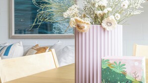 Una mesa de comedor con un florero de flores y un libro con una ilustración de naturaleza.