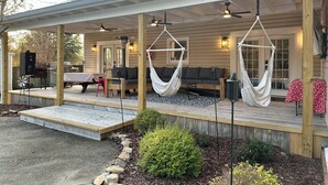 A covered outdoor area with a wooden deck, seating, and hammocks. - Bama Farmhouse - Beautiful Pool Area! (Tuscaloosa)