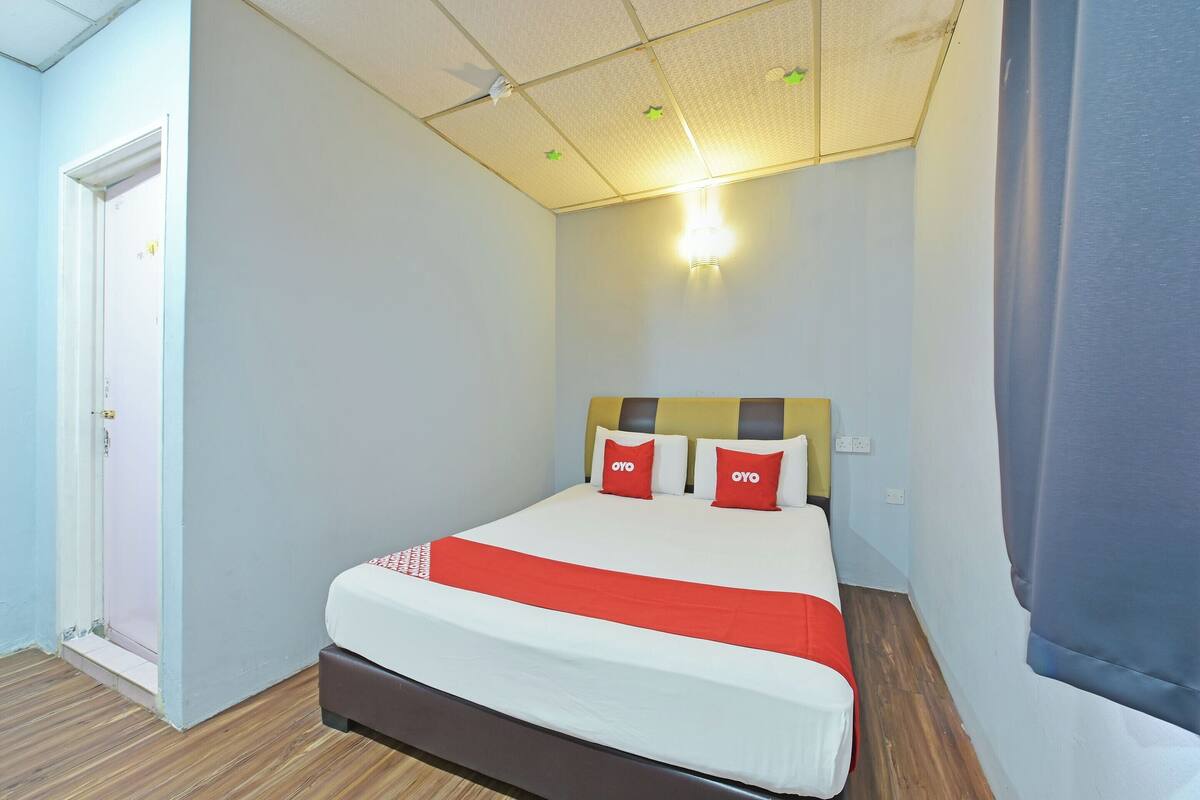 A neatly arranged hotel room with a bed, a door, and a light fixture on the ceiling.