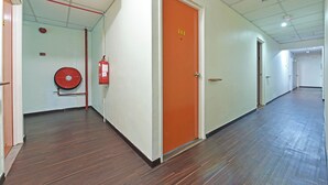 A hallway with an orange door marked "114", a fire extinguisher mounted on the wall, and a wooden floor. - OYO 90846 Hotel Akasia (Sungai Petani)