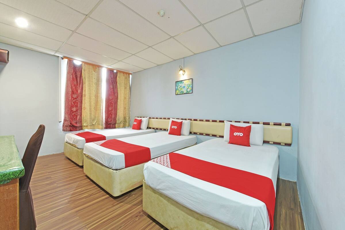 A hotel room with four single beds, a wooden desk, and a chair.