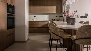 Eine moderne Küche mit Holzausbau, einem eingebauten Backofen, einer weißen Arbeitsplatte und einer Bar mit Hockern.