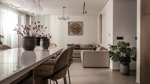 Ein modernes Wohnzimmer mit einer Couch, einem Esstisch mit Stühlen und einer großen Kübelpflanze.