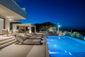 Zona de piscina exterior moderna amb seients de relaxació i zona de barbacoa.