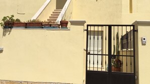 A two-story building with a beige facade, a black gate, and a staircase leading to the upper floor. - Olga's House  (Otranto)