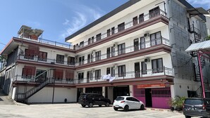 A multi-story building with a flat facade, multiple balconies, and a covered entrance area. - Hotel O Guest House Pandita (Tideng Pale)