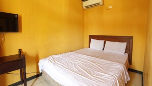 A room with a bed, a wooden nightstand, and a television mounted on the wall. - Hotel O Guest House Pandita (Tideng Pale)