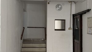 A hallway with a clock, a door, and a staircase leading to another room. - Hotel O Guest House Pandita (Tideng Pale)