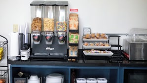 Un espace café en libre-service équipé de plusieurs distributeurs de boissons, d’une variété de collations et d’une machine à café de la marque « Kellogg’s ».