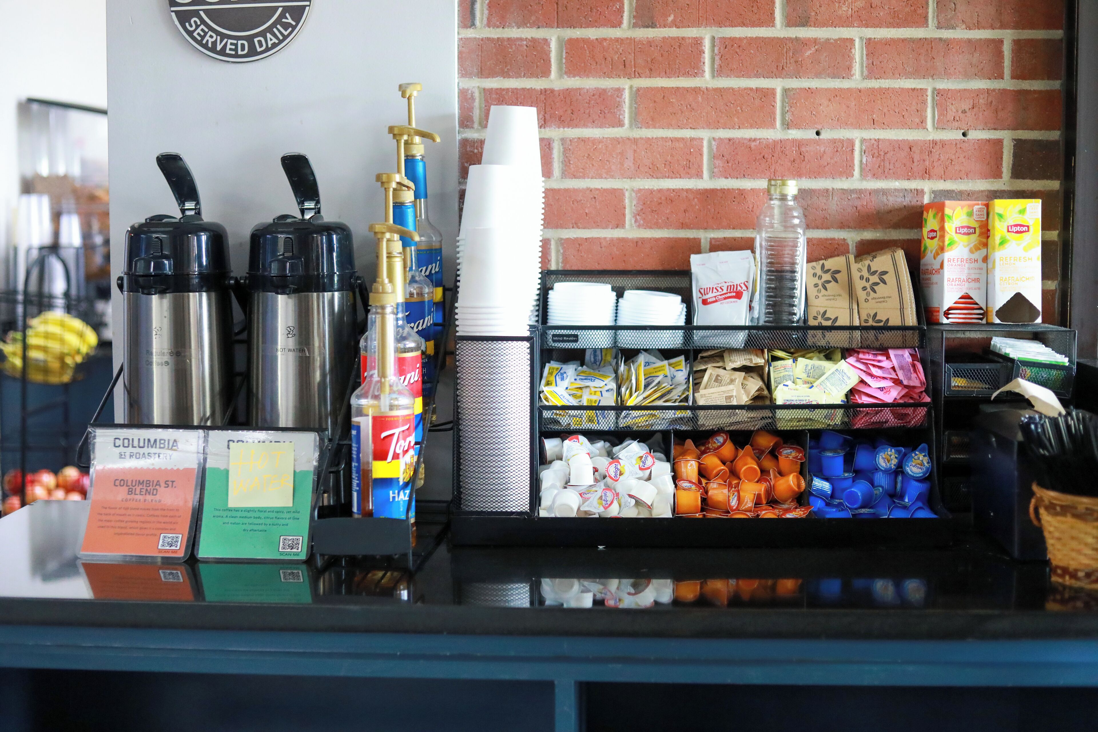 A coffee station with coffee makers, cups, and various coffee products.