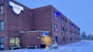 Un bâtiment en briques avec une enseigne indiquant « ILLINI INN & SUITES » et « Easy Stay ». Le bâtiment possède de nombreuses fenêtres et le sol est recouvert de neige.