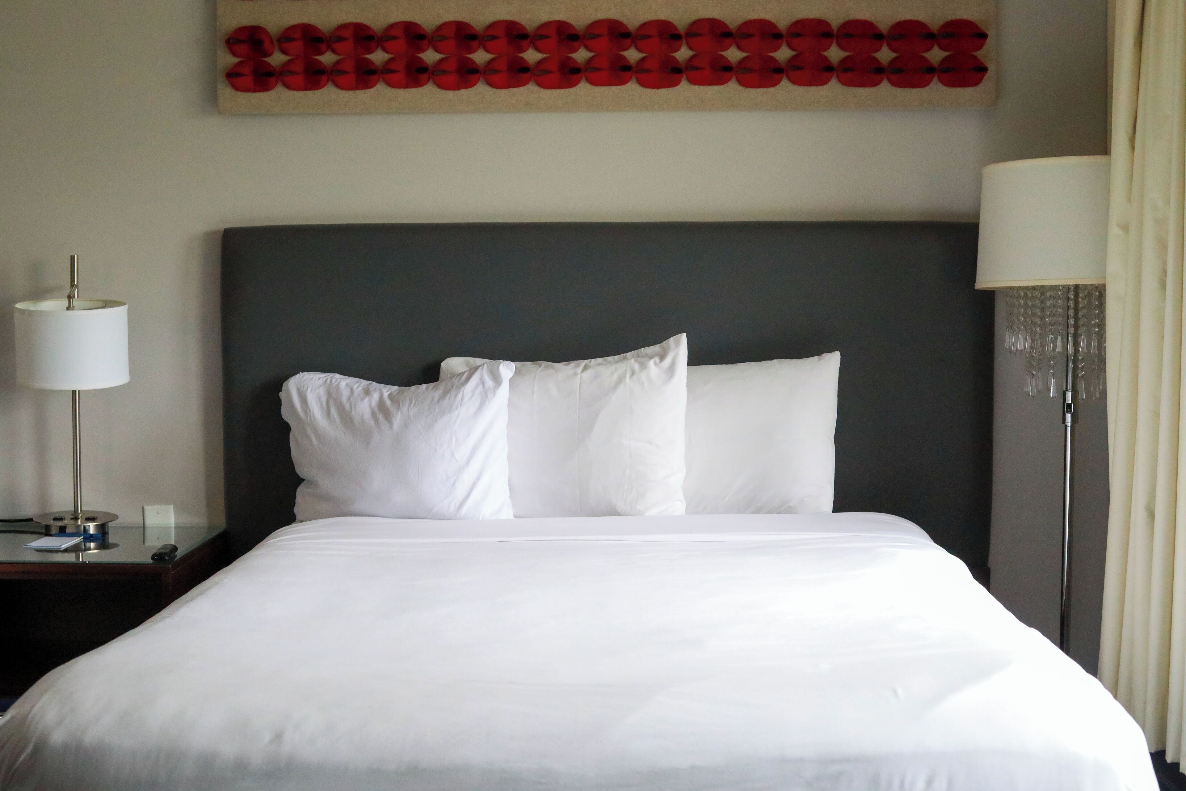 Habitación de hotel con una cama grande, una mesita de noche con lámpara y una obra de arte colgada en la pared.