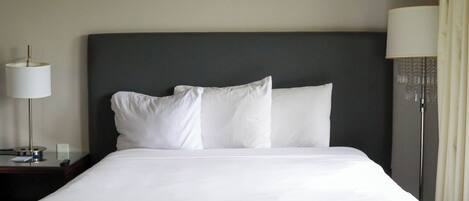 Habitación de hotel con una cama grande, una mesita de noche con lámpara y una obra de arte colgada en la pared.