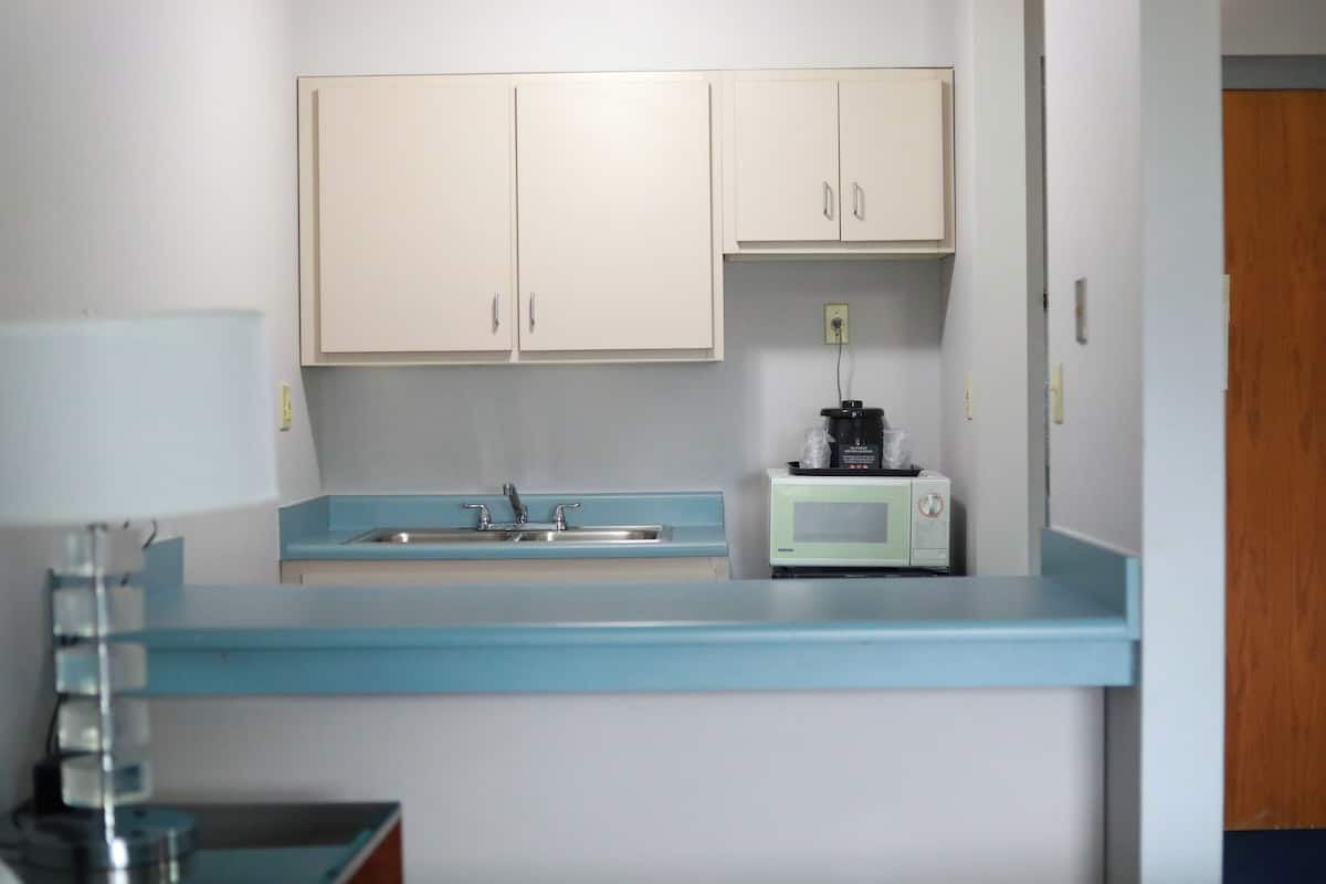 A kitchen with light blue countertops, a microwave, and a coffee maker.