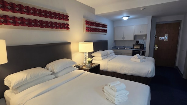 Une chambre d’hôtel avec deux lits, un bureau, une lampe et une kitchenette.