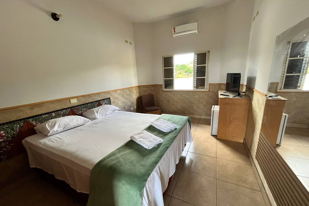 Ein Hotelzimmer mit einem Bett, einem Schreibtisch, einem Stuhl und einem Fenster.