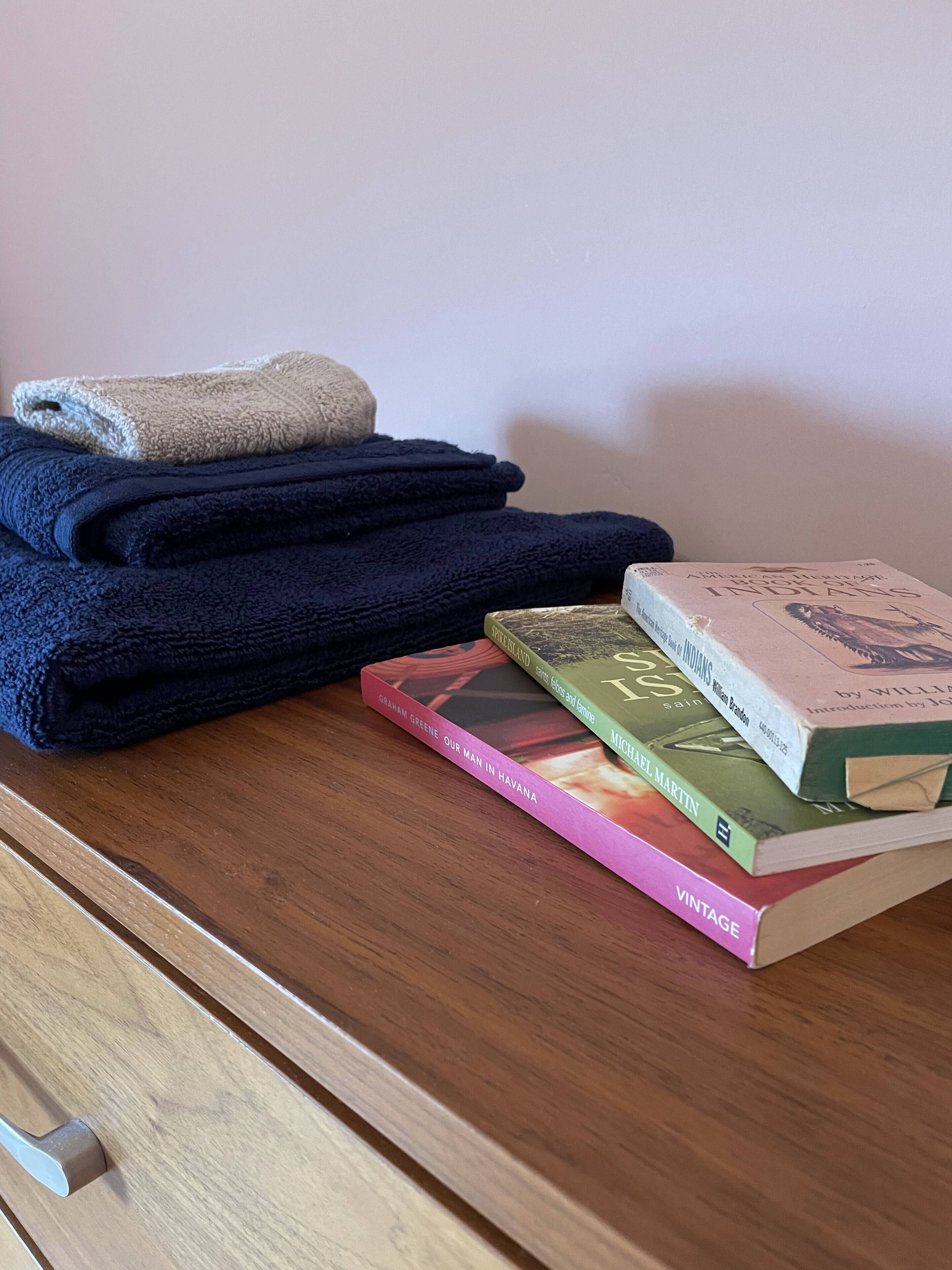 Una pila de toallas dobladas y una selección de libros sobre una superficie de madera.