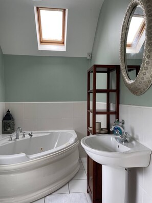 A bathroom with a freestanding bathtub, a sink, a mirror, and a small skylight. - A haven in the Orchard County. (Portadown)