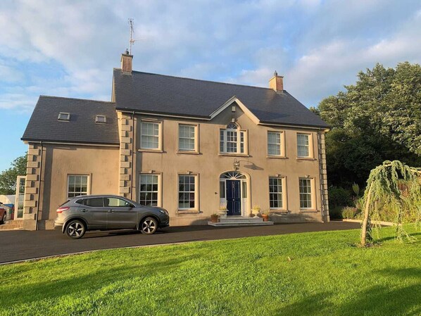 A two-story house with a driveway and a parked car. - A haven in the Orchard County. (Portadown)