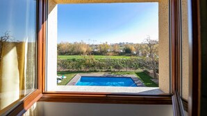 A view through a window of a backyard with a swimming pool, a grassy area, and a hedge. - Lake Views Quiet House, no Neighbors. Less Than 10min Walk From Beach and Shops (Platja d'Aro)