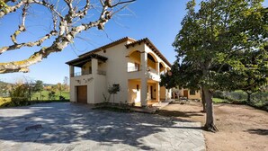 A two-story house with a stone-paved courtyard, a balcony, and a tree in the foreground. - Lake Views Quiet House, no Neighbors. Less Than 10min Walk From Beach and Shops (Platja d'Aro)