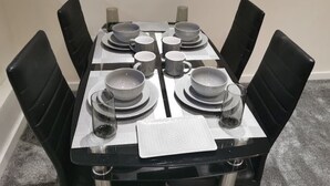 Une table à manger dressée avec des assiettes, des bols et des verres, entourée de chaises noires.