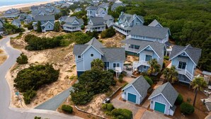 Zona residencial costeira com várias casas de dois andares, com varandas e garagens anexas.