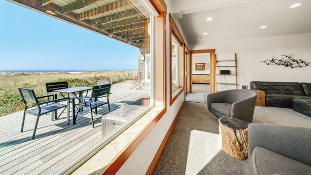Un vaste espace de vie avec vue sur la plage, une terrasse en bois et un mobilier moderne.