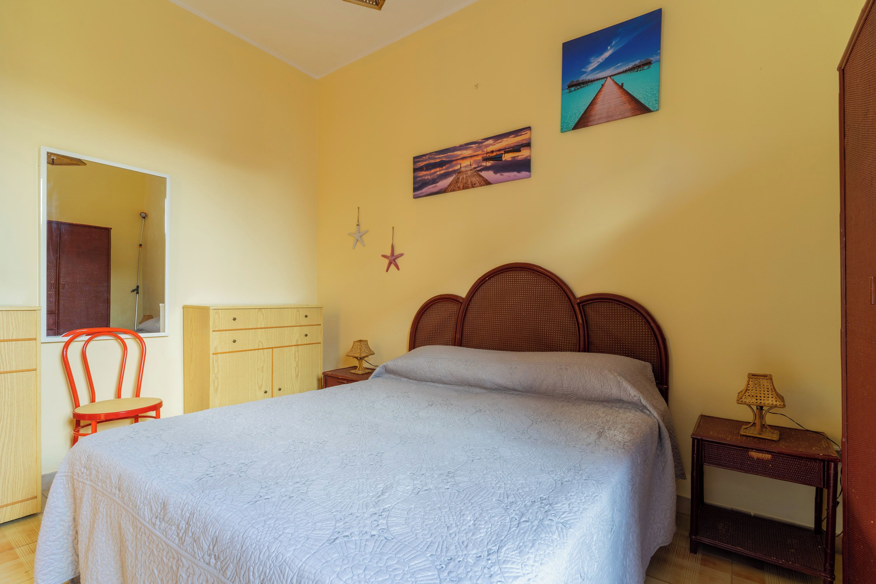 Une chambre à coucher avec un lit, une tête de lit en bois, une table de chevet avec une lampe et une fenêtre donnant sur un beau paysage.