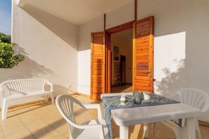A patio with a table and chairs, a wooden door, and a white wall. - 3464 Appartamento Rivabella by Barbarhouse (Gallipoli)