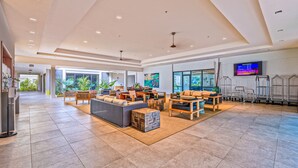A spacious lobby with a high ceiling, modern furniture, and a large screen displaying information. - Valley Isle Resort #1107 - Vacation West Maui - Beachfront Oasis (Lahaina)
