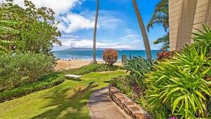 A pathway leading to a beach with palm trees and a view of the ocean. - Valley Isle Resort #1107 - Vacation West Maui - Beachfront Oasis (Lahaina)