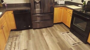A kitchen with wooden cabinets, a stainless steel refrigerator, a toaster, and a black oven.