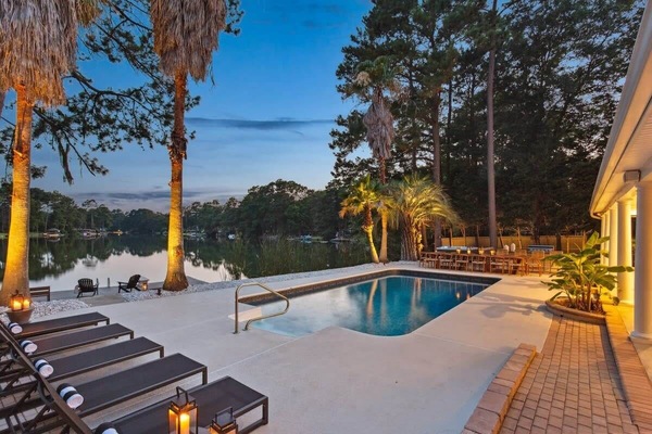 The outdoor space features a pool, dining table, bar & grill, and beautiful lake views!
