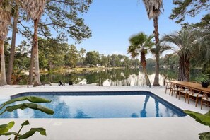 A swimming pool with a view of a lake and surrounding trees.