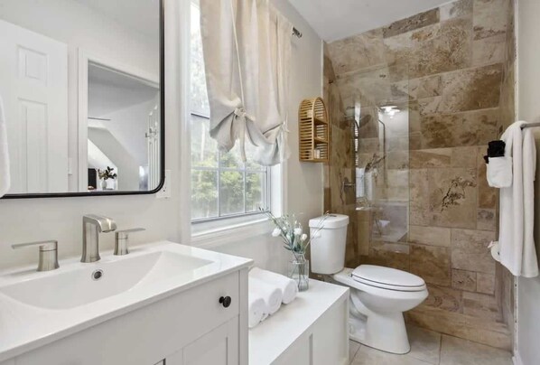Un baño moderno con un lavabo, tocador y retrete blancos.