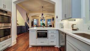 A modern kitchen with white cabinetry, a central island, and a Bosch oven. - Houston Centrally Located w/ Backyard Pool Retreat (Houston)