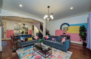 A spacious living room with a sofa, coffee table, and colorful rug.