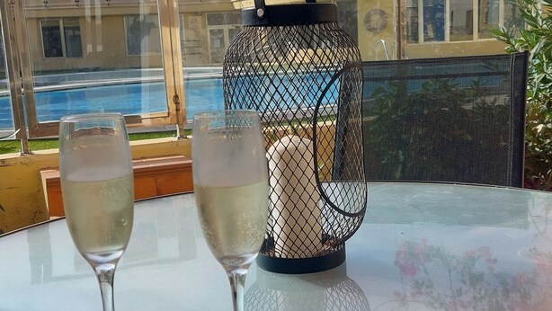 Ein Tisch mit zwei Weingläsern, einer dekorativen Laterne und Sonnenbrillen.