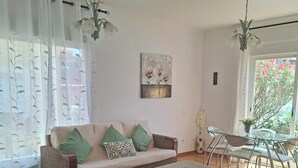 Ein Wohnzimmer mit einer Couch, zwei Sesseln, einem Couchtisch und einem Essbereich mit Stühlen und einem Tisch.