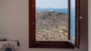 Una habitación con vistas a un paisaje montañoso y al mar.