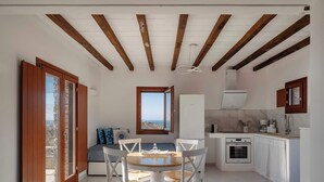 Cocina compacta con comedor, horno empotrado y vista al mar a través de un ventanal.