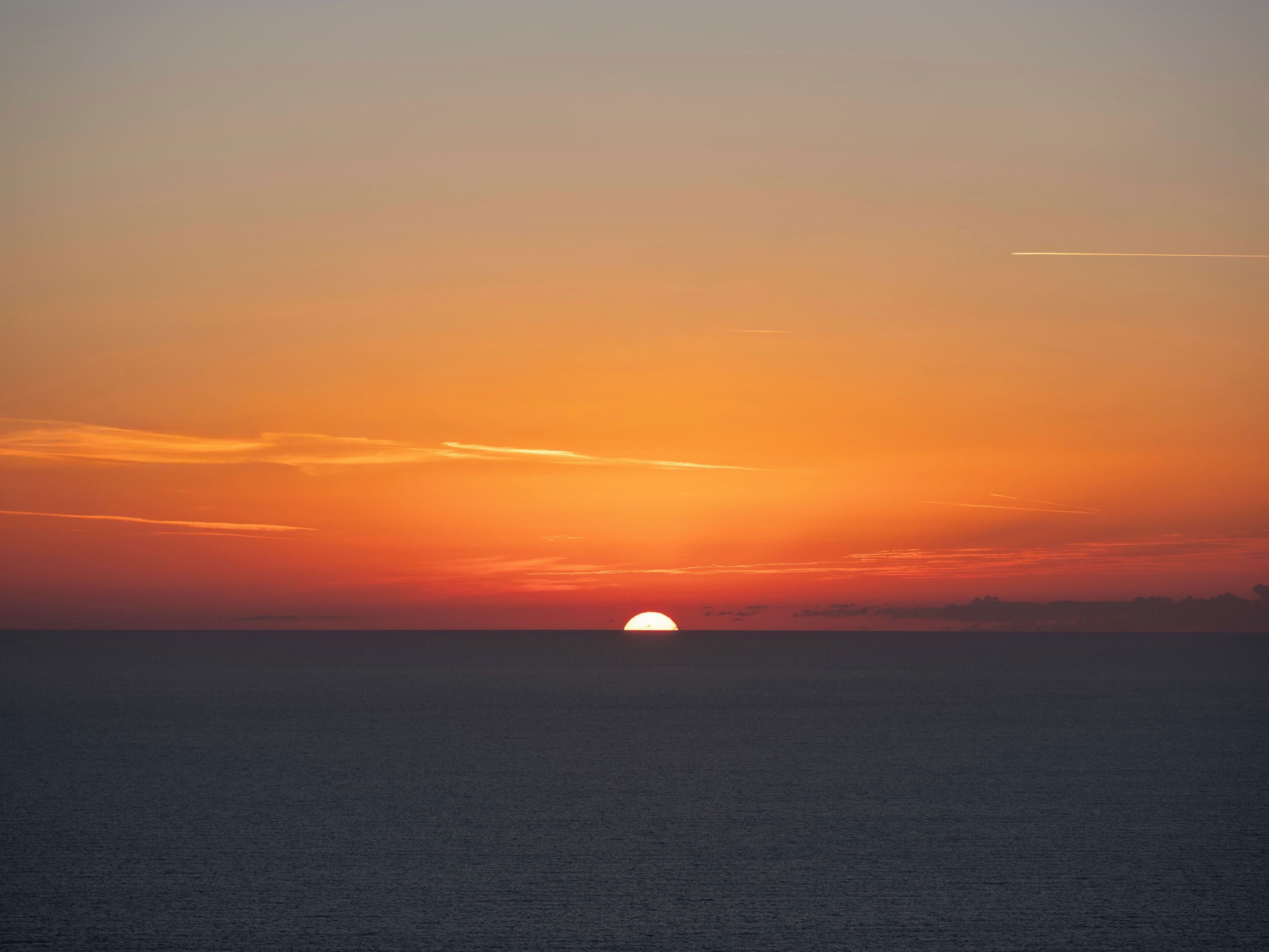 Un atardecer sobre un mar tranquilo con horizonte visible.