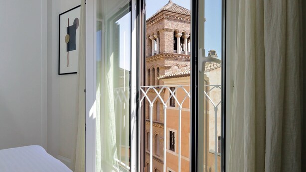 Una habitación con un amplio ventanal que da a un edificio histórico con una torre.